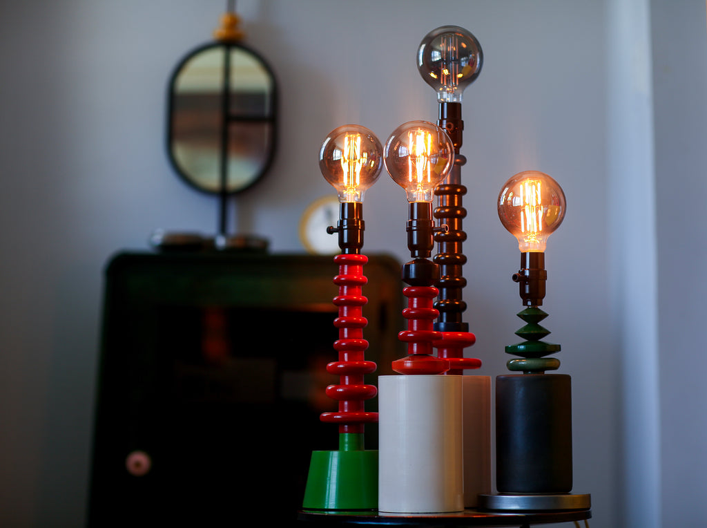 Three unique lamps with glowing bulbs on a blurred background.