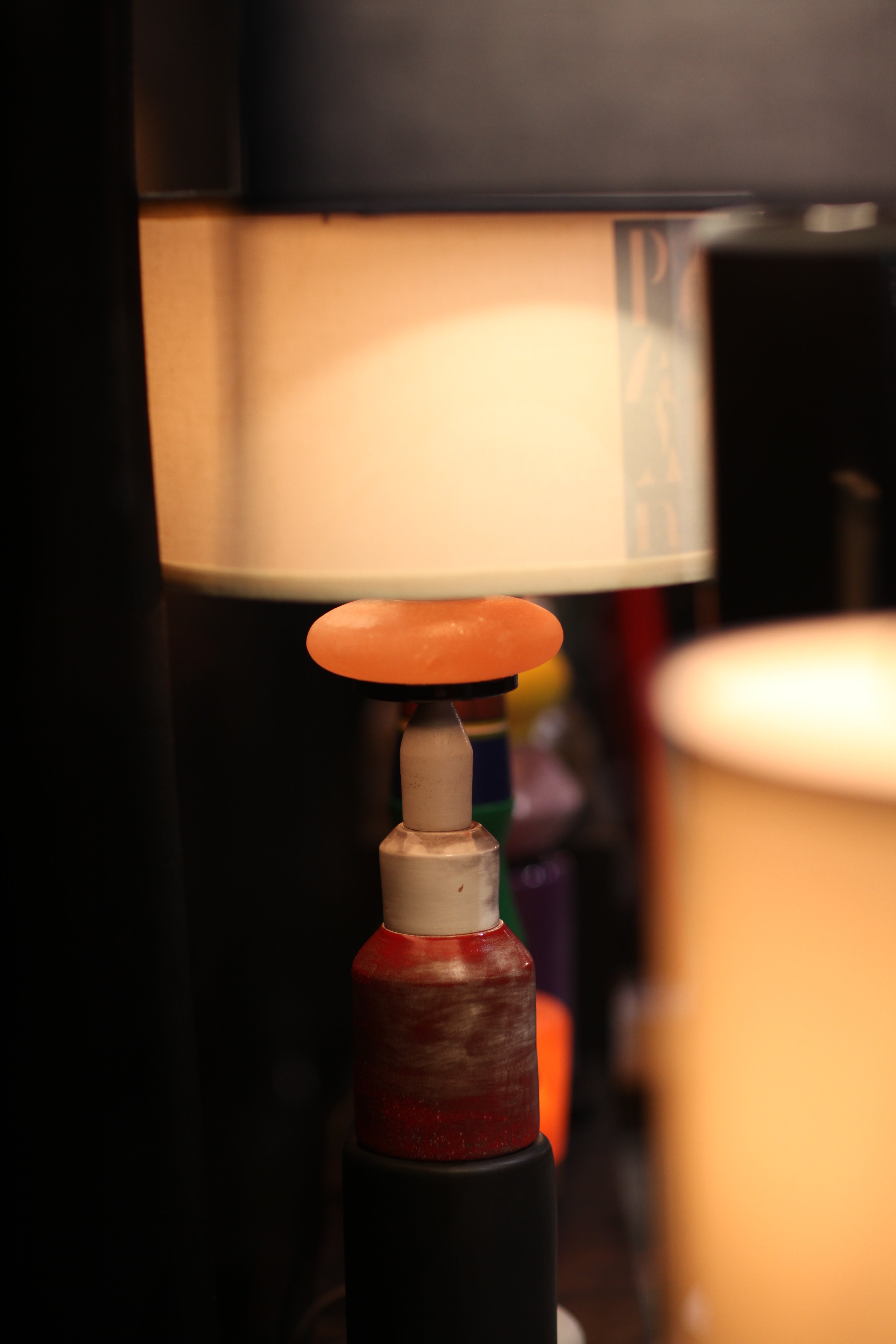 A close-up action shot of a rotary tool with a round orange abrasive bit spinning against a light-colored workpiece, illuminated by warm light.